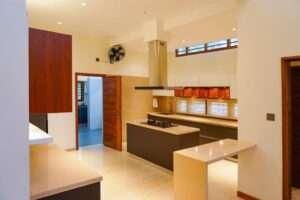 Spacious modular kitchen with an island counter, sleek cabinetry, warm lighting, and a modern chimney setup.