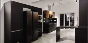Contemporary modular kitchen with dark wood finishes, island counter, premium cabinetry, and modern appliances by Nishan Interio – Contact for Custom Kitchen and Wardrobes in Uttarakhand